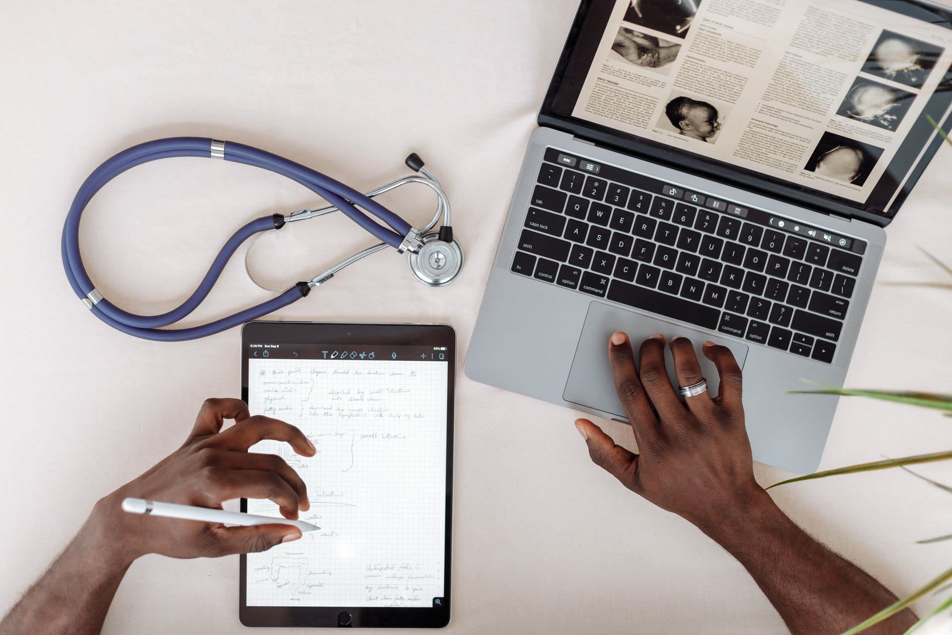 A clinician's desk with a stethoscope, tablet and laptop