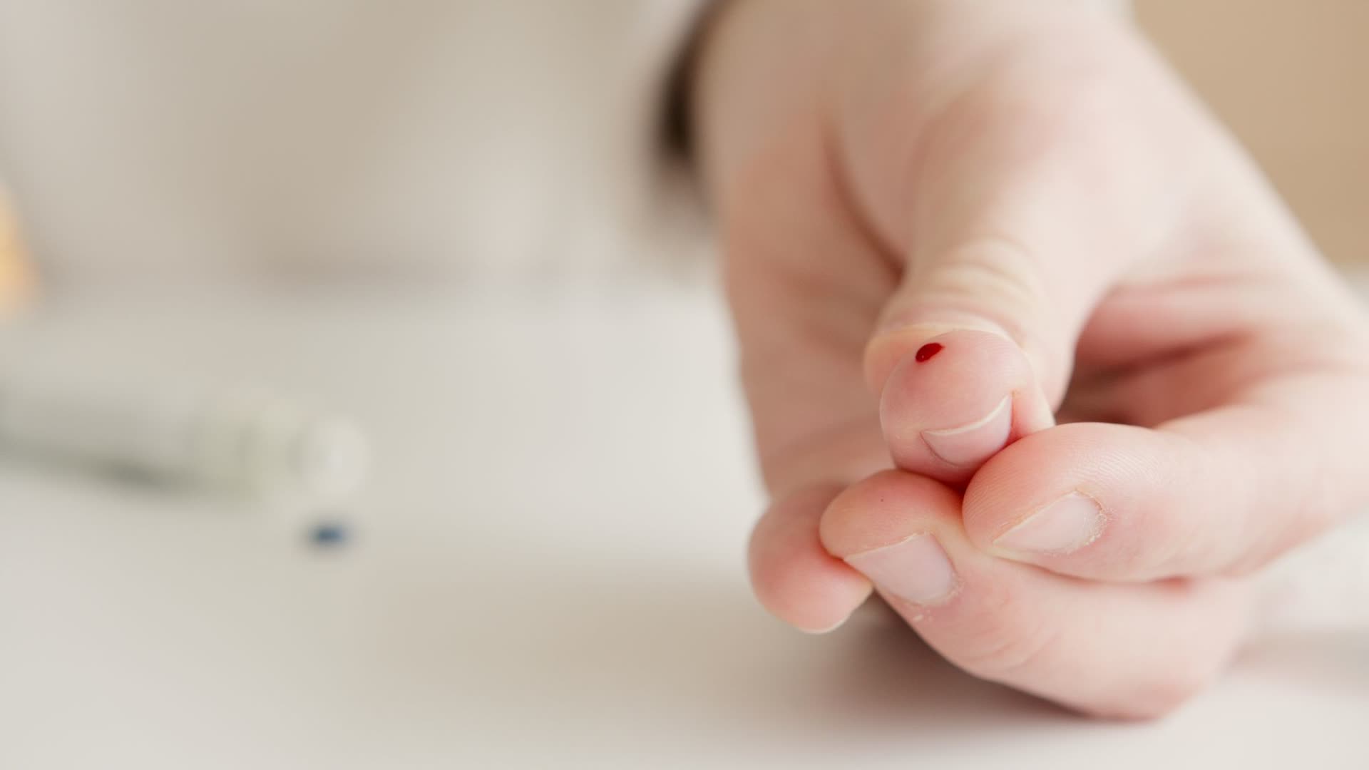 A fingertip with a single drop of blood after a painless lancet prick